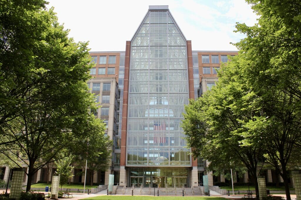 Glass-front atrium building framed by leafy trees
